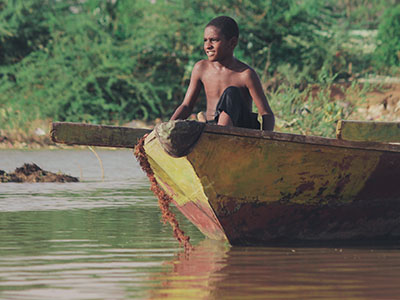 A child in a rusty boat floating on dirty water