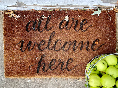 Welcome mat that says, "All are welcome here."